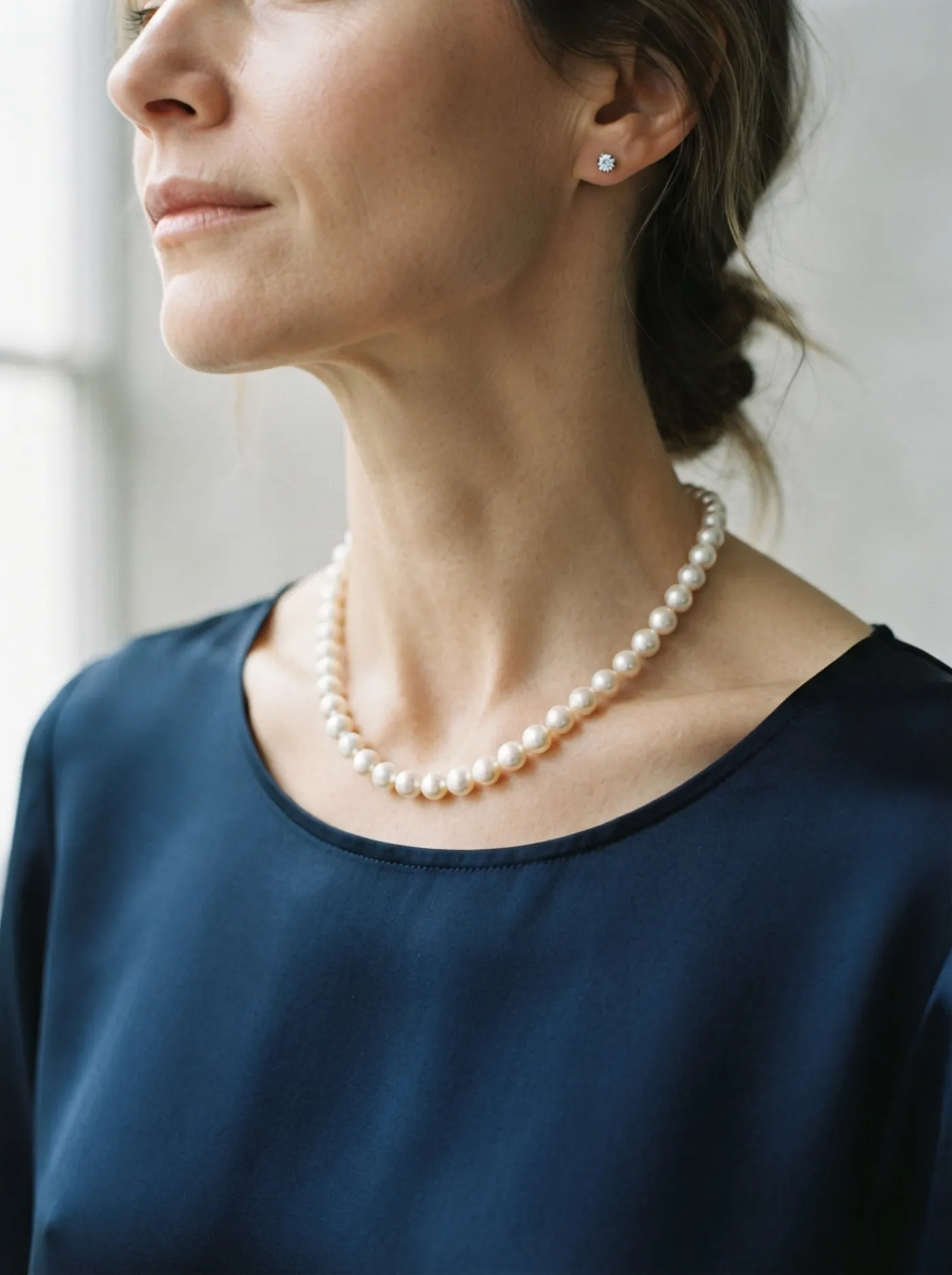 A pearl strand and diamond studs worn with a navy silk dress